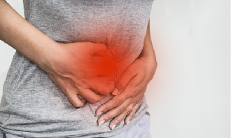 Una mujer se pone las manos en la barriga al sentir dolor en el intestino