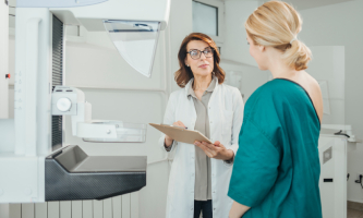 Mujer joven habla con su doctora para realizar una mamografía 